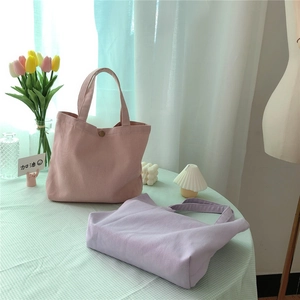 Detailed texture of pink and purple corduroy tote bags with vintage metal button closure