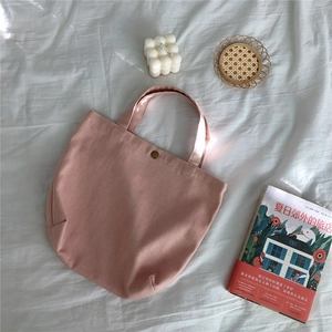 Top view of dusty rose canvas handbag with vintage metal button and textured fabric background