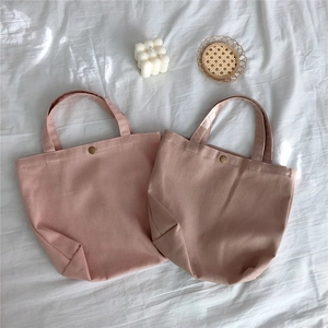 Macro shot of two pink twill canvas tote bags showing metal snap button detail