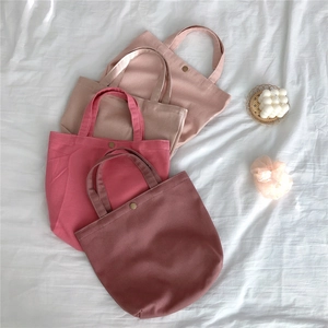 Detail view of four Morandi pink canvas tote bags with metal snap buttons and handles
