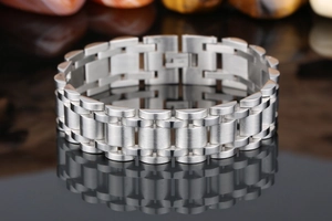 Macro detail of men's wide stainless steel chain bracelet with brushed silver texture