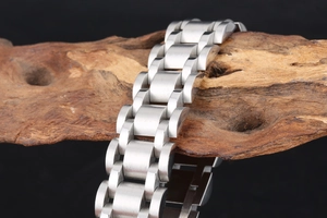 Detailed view of brushed silver stainless steel link bracelet on natural wood base