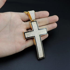 Macro view of gold-plated iced-out cross pendant with black enamel and clear rhinestones