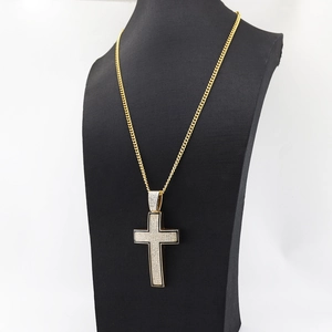 Macro detail of a gold iced-out cross pendant on a thick Cuban chain for men