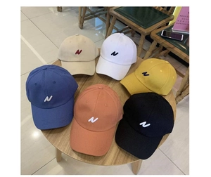 Vue de dessus de casquettes en six couleurs avec broderie lettre N sur table en bois