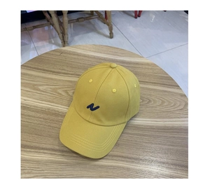 Gros plan d'une casquette jaune avec broderie lettre N bleue sur une table en bois