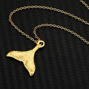 Elegant gold mermaid tail necklace with detailed scale texture on a black background