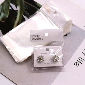 Detailed view of self-adhesive OPP jewelry bags with white card headers and gold text