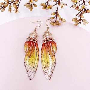 Detailed macro view of cicada wing earring with orange gradient resin and gold flakes