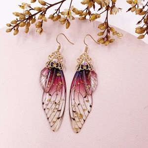 Detailed view of handmade cicada wing earrings with purple gradients and gold foil accents