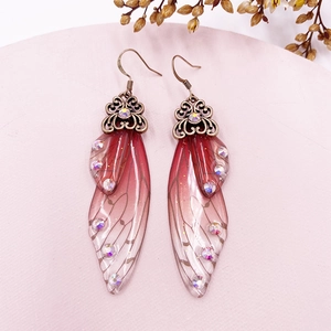 Detailed close-up of cicada wing earrings with red gradient and sparkling rhinestones