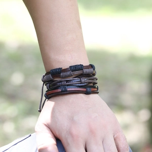 Close-up of layered woven leather bracelets in black and brown on a male wrist