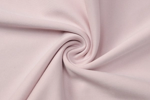 Detailed macro view of light pink knitted fabric texture with a fine mesh weave pattern