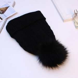 Thick black cable knit beanie with faux fur pom pom and ribbed cuff for winter warmth