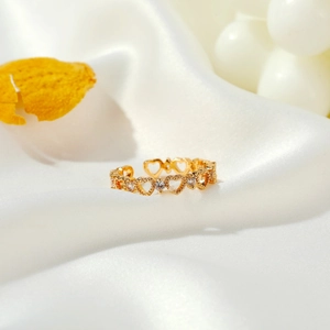 Hollow heart-shaped open ring in gold with sparkling crystals on white satin
