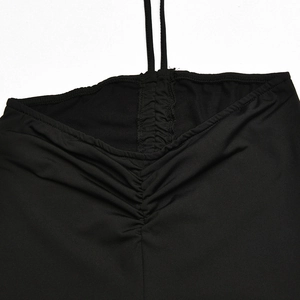 Detail of black halter top featuring deep V-neck pleats and elastic fabric texture