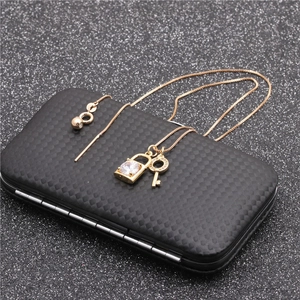 Dettaglio del set collana e orecchini dorati con ciondolo a lucchetto e chiave in zircone