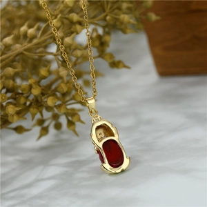Golden Pi Xiu necklace with red crystal pendant and stainless steel chain on marble surface