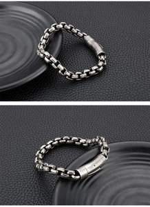 Detail van vintage stalen kettingarmband met magnetische sluiting op zwart leer