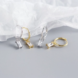 Detail of silver and gold hoop earrings with rectangular cubic zirconia charms