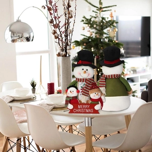 Detail of plush Christmas snowman ornaments with Merry Christmas sign on a festive table
