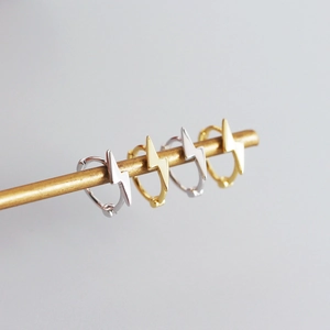 Dettaglio di orecchini a cerchio minimalisti a fulmine in finitura argento e oro