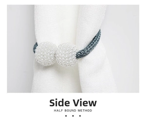 Close-up of blue braided curtain tieback with white pearl magnetic buckles on fabric