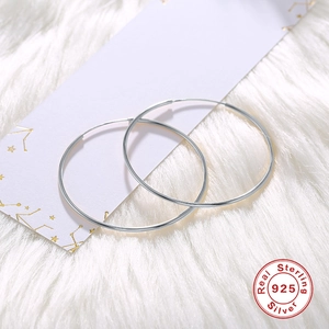 Classic 925 sterling silver hoop earrings for women on soft textured background