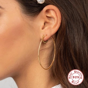 Polished 925 sterling silver large gold hoop earrings worn by a model
