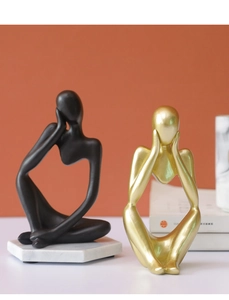 Detail of modern minimalist abstract thinker statues in black and gold on marble bases