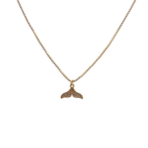 Close-up of golden whale tail pendant with micro-paved zircons on a box chain