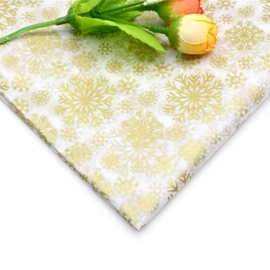 Close-up of tissue paper with gold snowflake pattern and decorative yellow buds