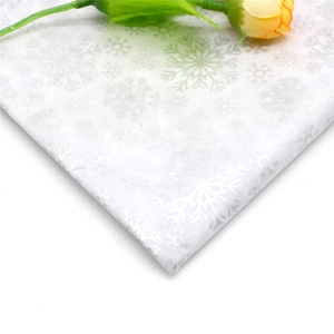 Detail of white tissue paper featuring silver glitter snowflake patterns for gift wrapping