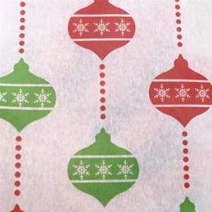Macro detail of Christmas wrapping paper with red and green ornaments on white tissue