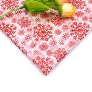 Close-up of red and white snowflake pattern tissue paper with decorative yellow roses