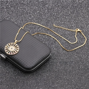 Close-up of golden Evil Eye necklace pendant with colorful zircons on a black box