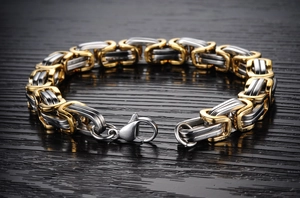 Close-up of two-tone gold and silver Byzantine chain bracelet on a dark wood background