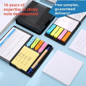 Close-up of portable leather memo set with neon sticky notes and paper pen on blue background