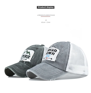 Detail of distressed trucker hats featuring explorer and girl patches with breathable mesh