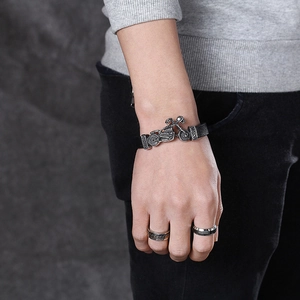Men's punk leather bracelet with silver skull motorcycle buckle on a grey rock background