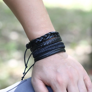 Close-up of four layered black braided leather bracelets showing rich handmade textures