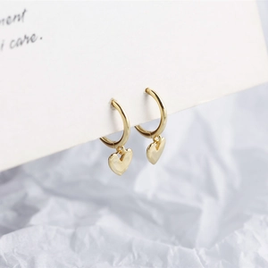 Detailed view of elegant gold heart pendant hoop earrings on minimalist white card