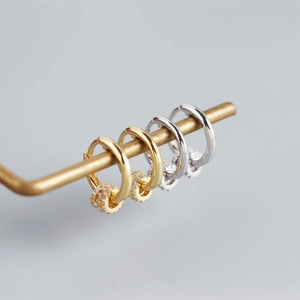 Close-up of S925 silver earring hoops with micro-pave crystals on metal display rack