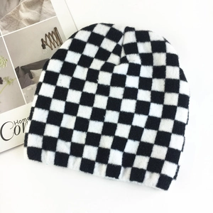 Close-up of a black and white checkerboard knit beanie hat on a minimalist background