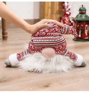 Detailed view of a Christmas gnome topper with red knitted snowflake hat on wooden floor