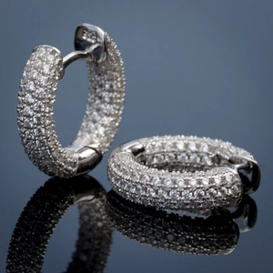 Pave set cubic zirconia huggie earrings in silver metal with elegant mirror reflection
