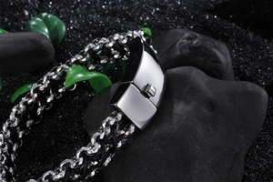 Macro detail of silver stainless steel magnetic clasp and black braided leather bracelet
