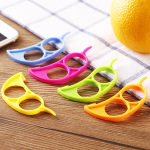 Five-color plastic citrus peeler set with ring design on wooden table with orange