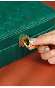 Close-up of golden metal lock on dark green leather jewelry box with quilted stitching