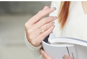 Luxurious gold bow ring with pavé-set crystals worn on finger over an open book